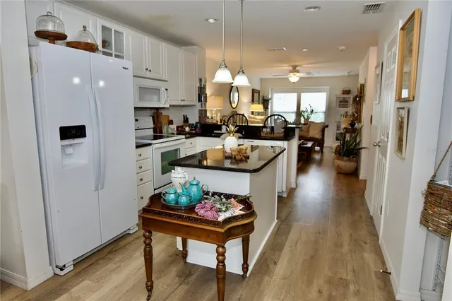 a kitchen with a refrigerator a stove and white cabinets with wooden floor