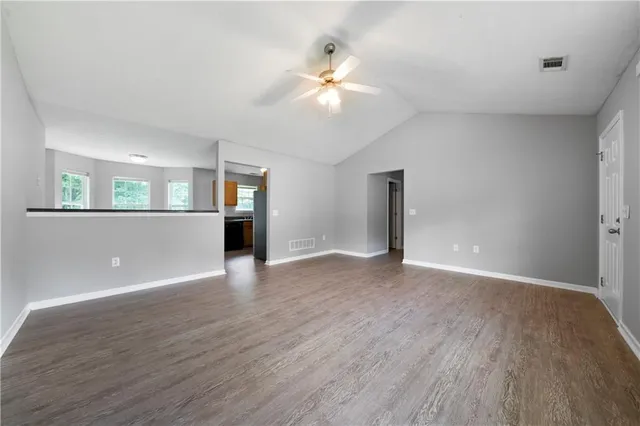 a view of an empty room with window and wooden floor