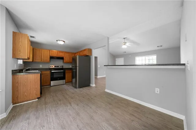 a kitchen with stainless steel appliances granite countertop a refrigerator a sink a stove and oven