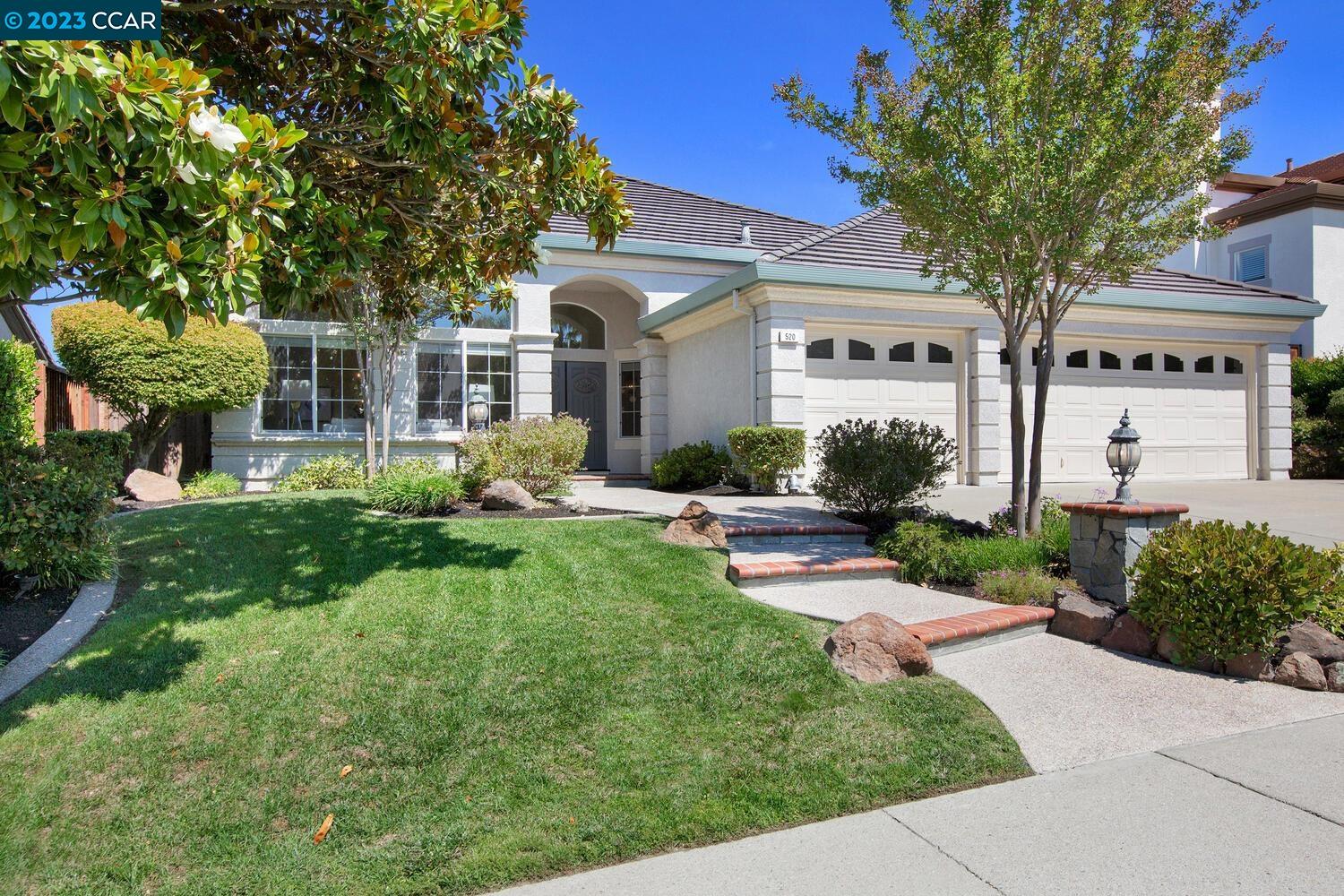 a front view of a house with garden and trees