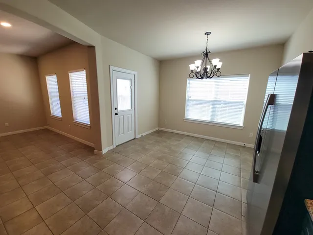 an empty room with chandelier and windows