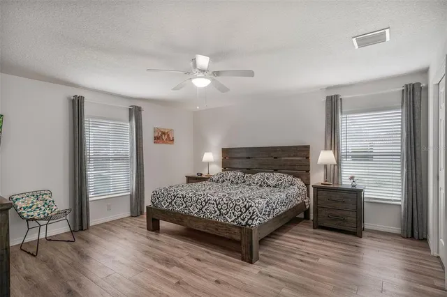a bedroom with a bed a dresser and wooden floor