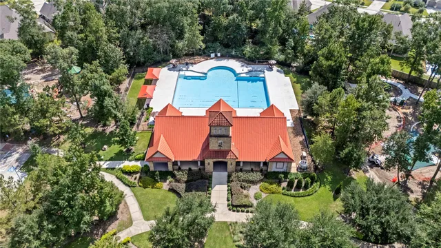 an aerial view of a house with swimming pool and trees