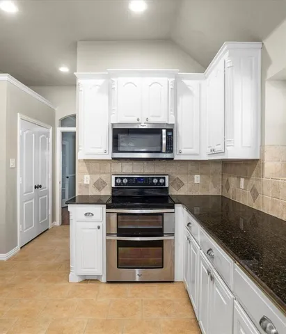 a kitchen with stainless steel appliances granite countertop a sink a stove and a refrigerator