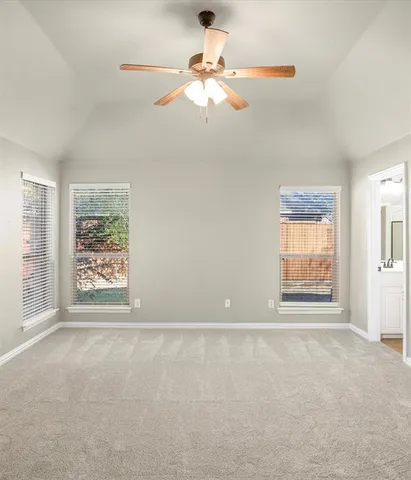 an empty room with chandelier fan and windows