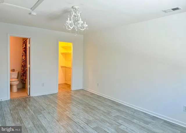 an empty room with wooden floor chandelier and closet