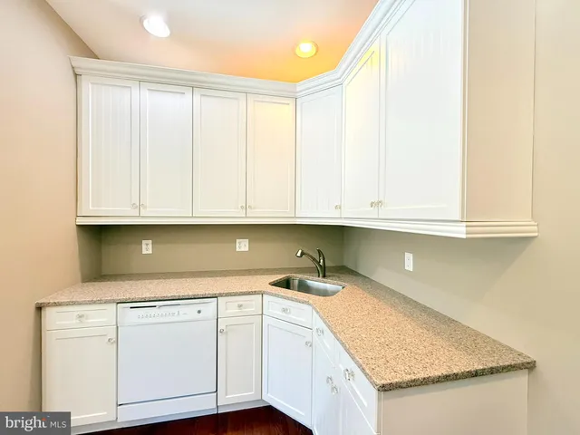 a kitchen with granite countertop white cabinets and sink