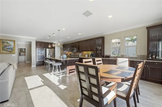 a dining area with stainless steel appliances kitchen island granite countertop a dining table chairs and view living room