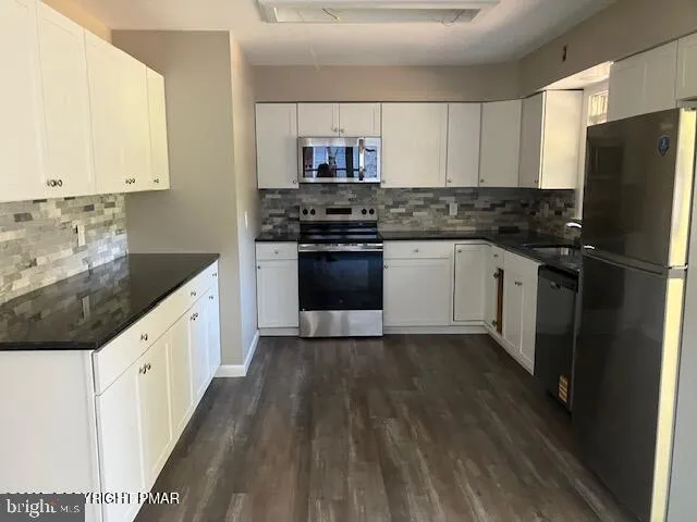 a kitchen with granite countertop white cabinets and stainless steel appliances