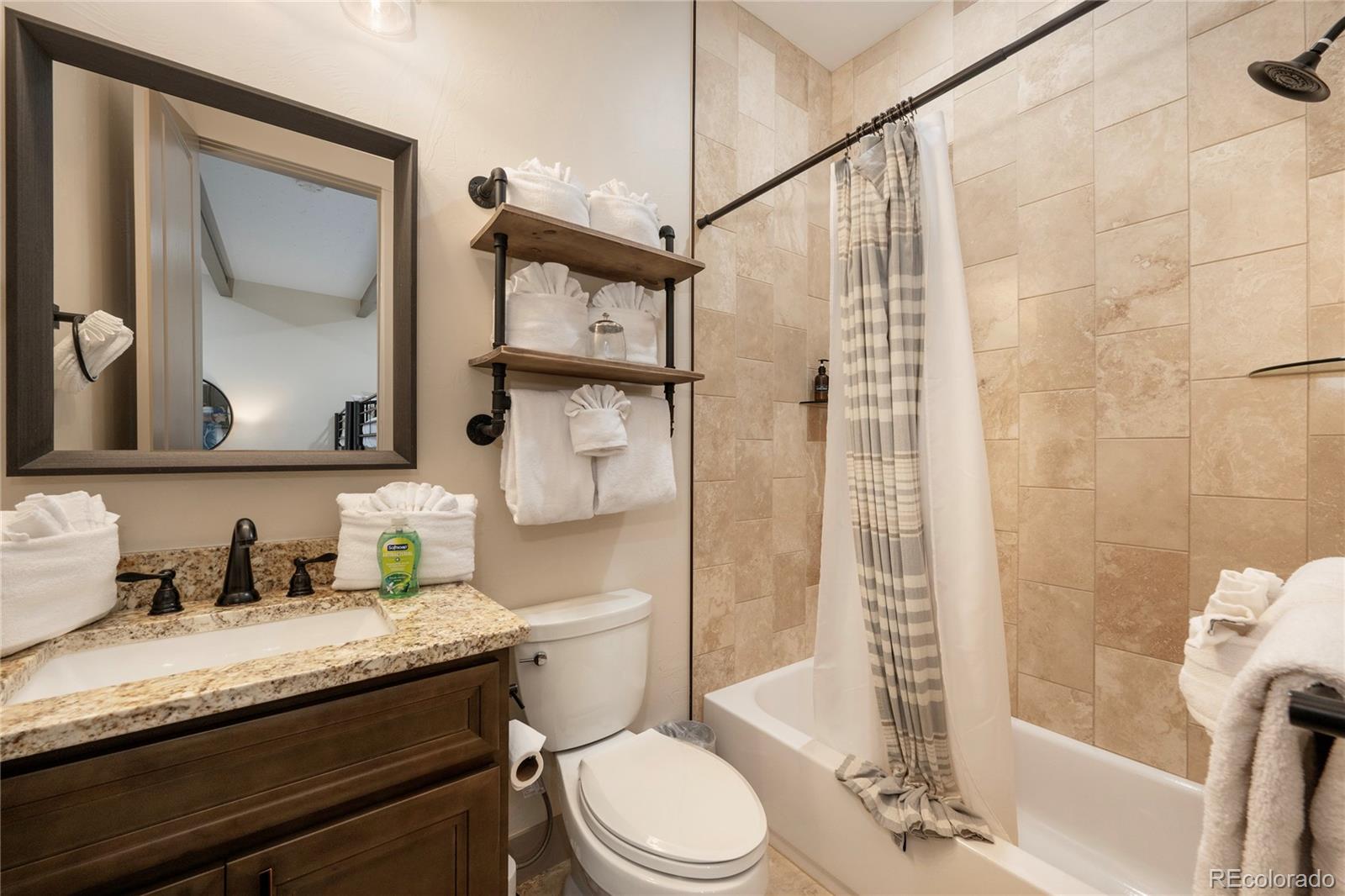 465 Lower Ranch View Drive Granby, CO 80446 - Photo 29 of 50 a bathroom with a granite countertop sink toilet a mirror and shower