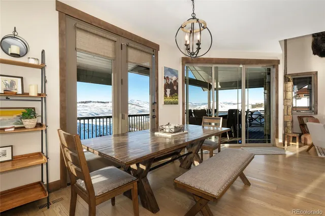 a dining room with wooden floor a chandelier a wooden table and chairs
