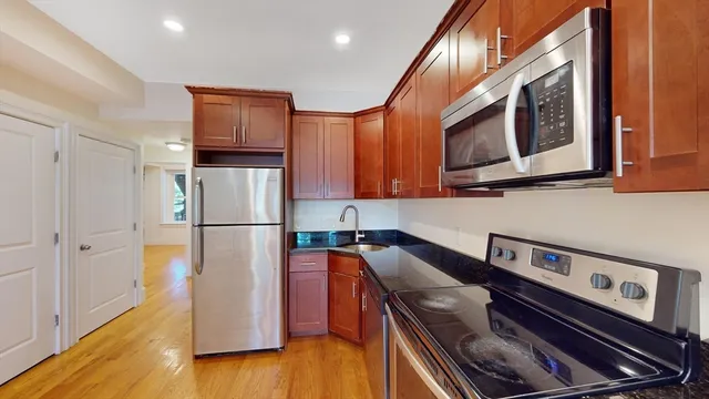 a kitchen with stainless steel appliances granite countertop a refrigerator a stove and a wooden floor