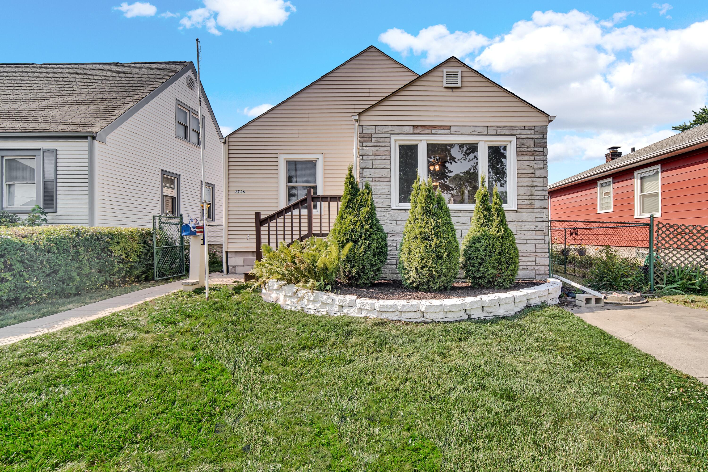 a view of a white house with a small yard and potted plants