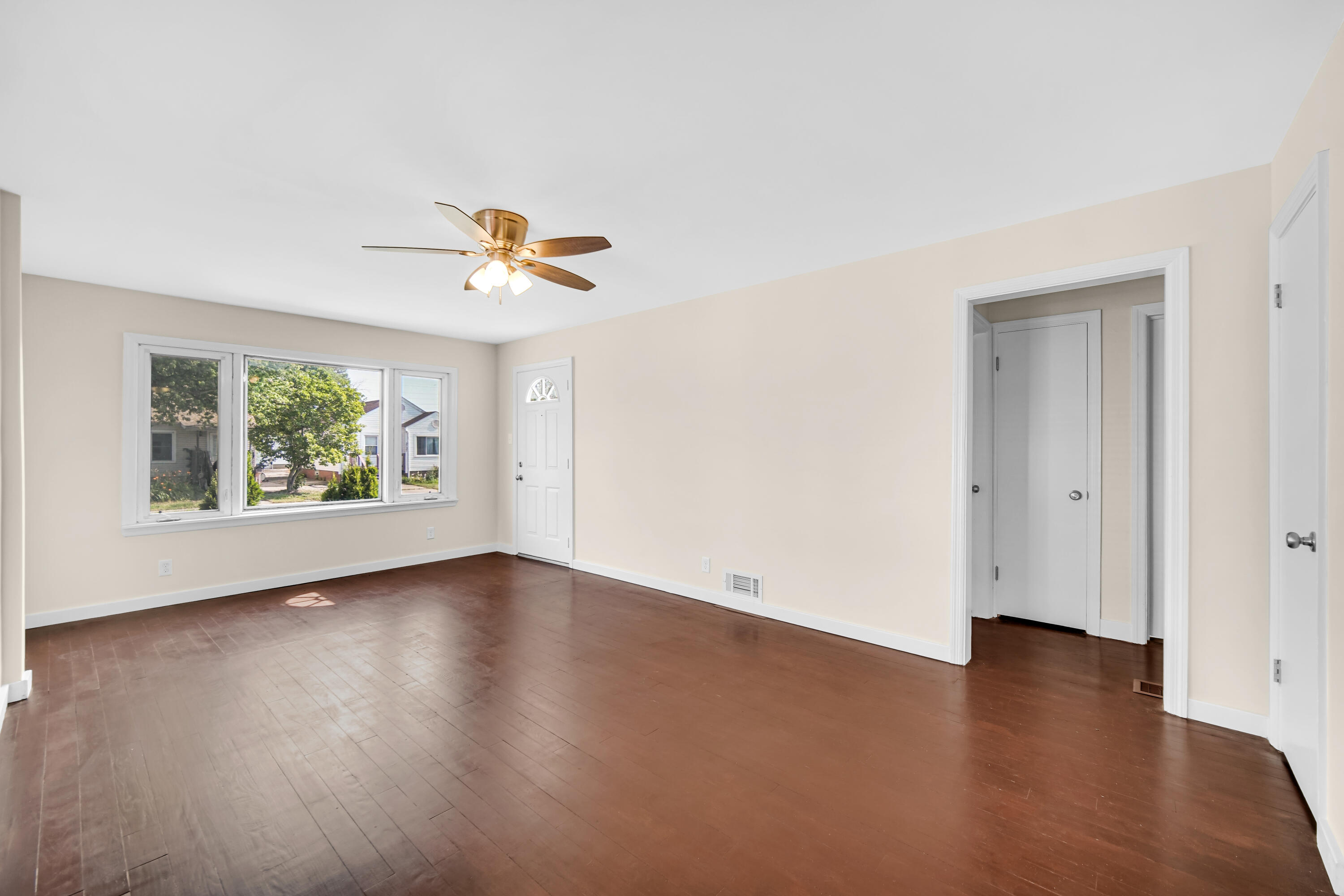 2726 162nd Place Hammond, IN 46323 - Photo 2 of 18 an empty room with window a ceiling fan and wooden floor