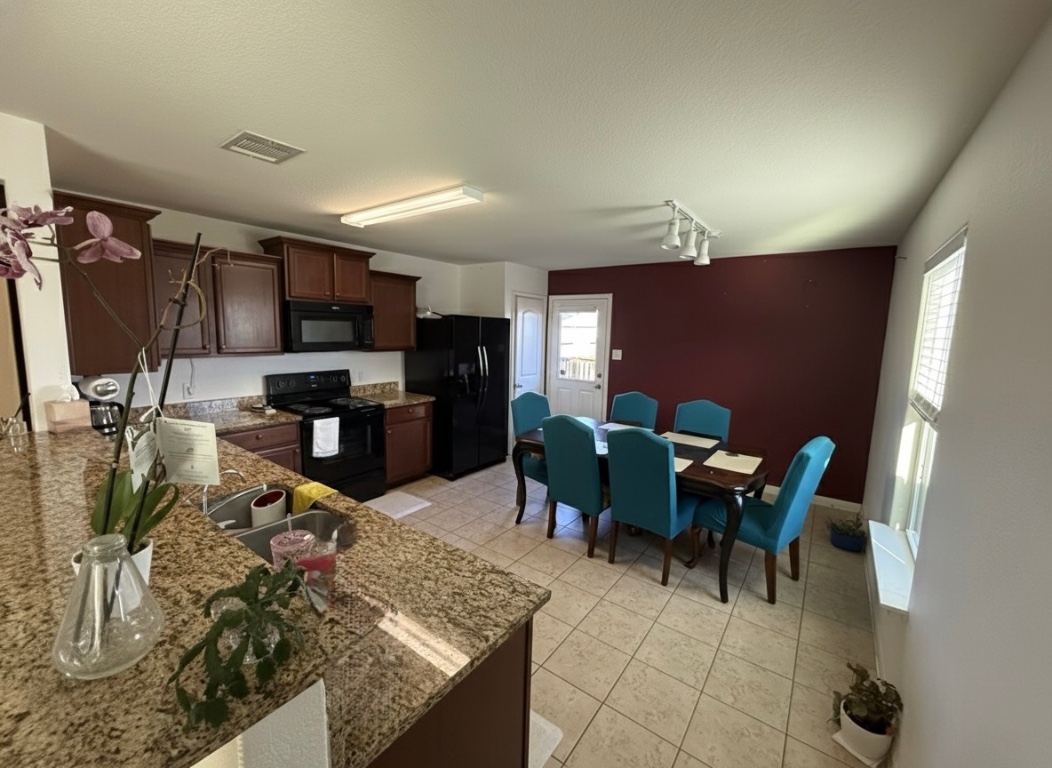 108 Koontz Loop Jarrell, TX 76537 - Photo 4 of 20 Kitchen featuring dark brown cabinetry, black appliances, track lighting, light stone countertops, and light tile patterned floors