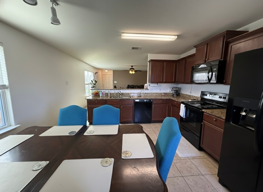 108 Koontz Loop Jarrell, TX 76537 - Photo 5 of 20 Kitchen with black appliances, dark stone counters, dark brown cabinetry, light tile patterned floors, and a peninsula