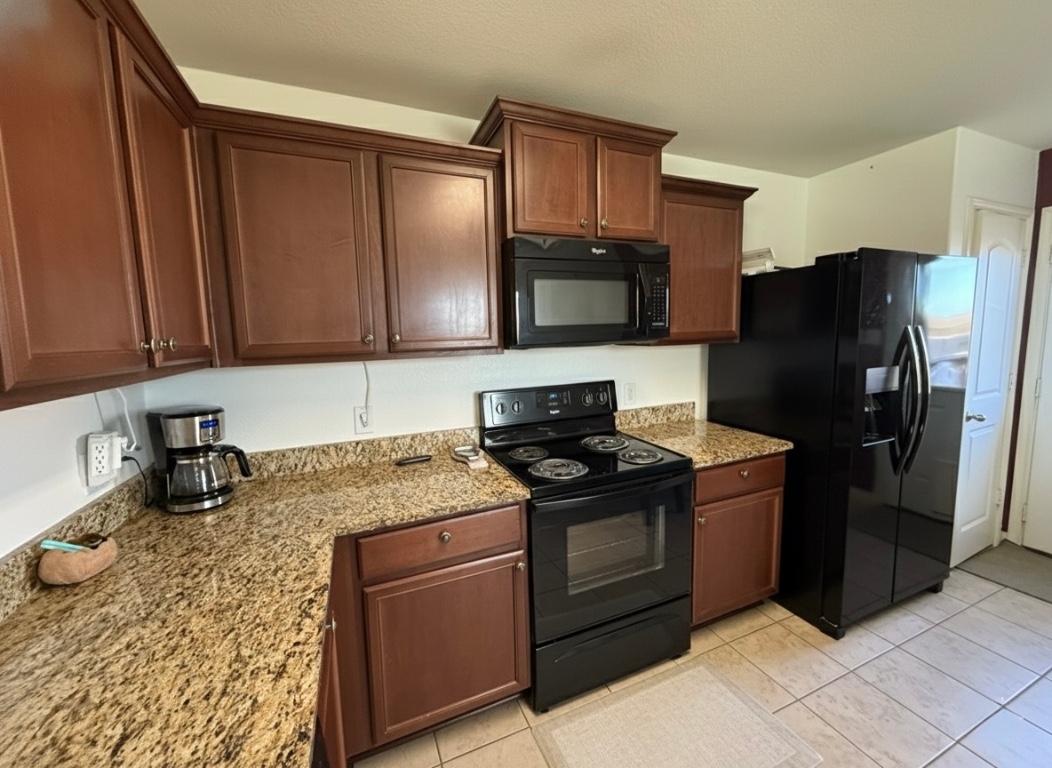108 Koontz Loop Jarrell, TX 76537 - Photo 7 of 20 Kitchen featuring black appliances, light stone counters, dark brown cabinetry, and light tile patterned floors