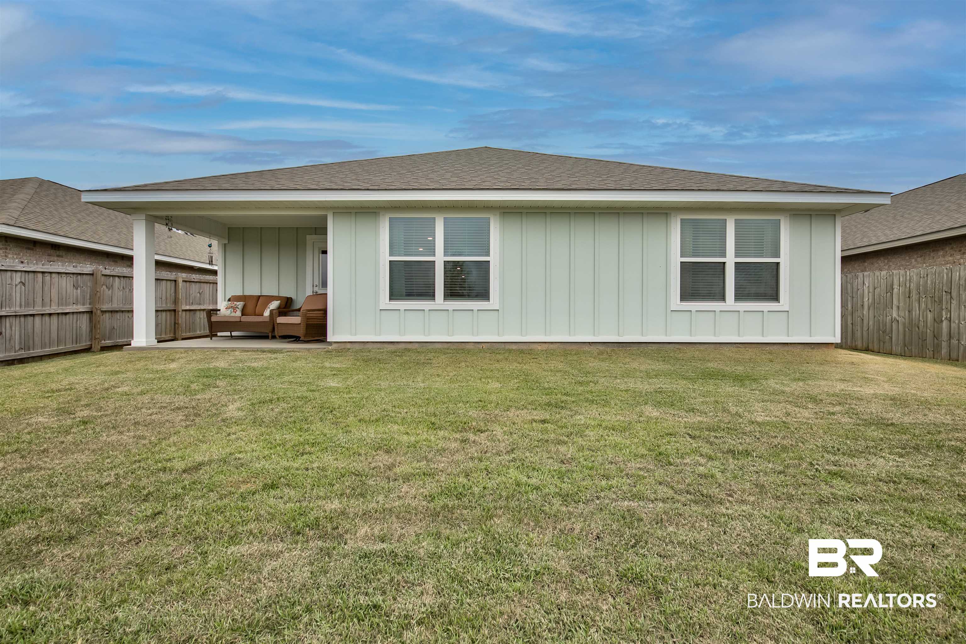 8033 Irwin Loop Daphne, AL 36526 - Photo 38 of 38 Expansive rear yard featuring a covered patio, board and batten siding, multiple windows, and a privacy fence
