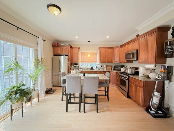 a kitchen with stainless steel appliances granite countertop a refrigerator a stove top oven a sink dishwasher and white cabinets with wooden floor