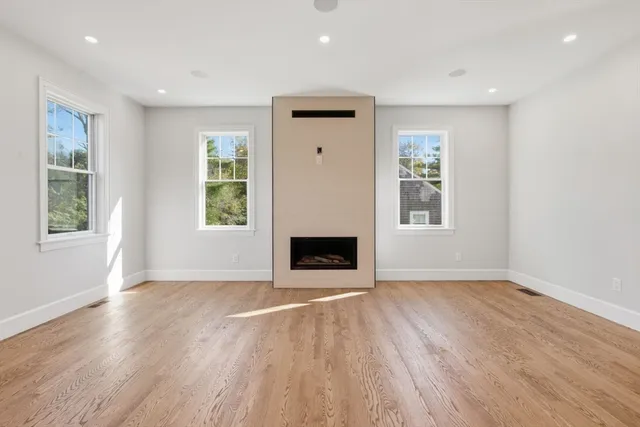 an empty room with windows and fireplace