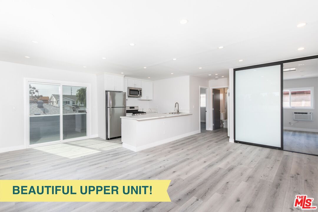 a view of kitchen with stainless steel appliances kitchen island wooden cabinets and refrigerator