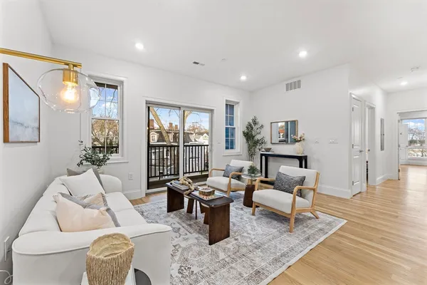 a living room with lots of furniture a rug and kitchen view