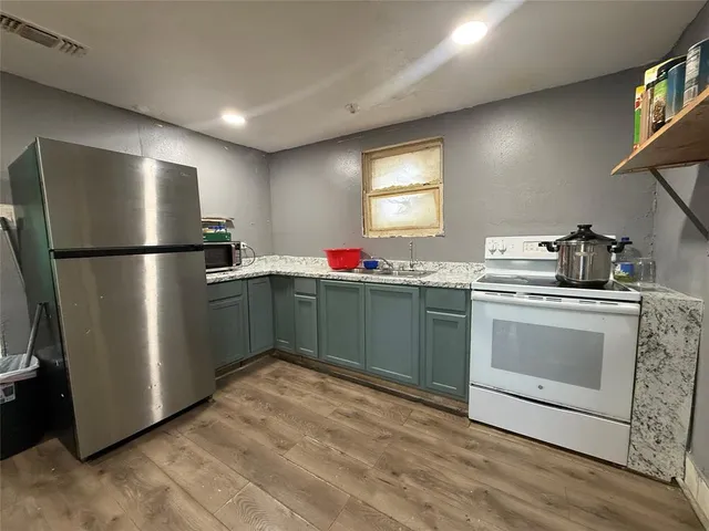 a kitchen with stainless steel appliances granite countertop a refrigerator sink and wooden floor