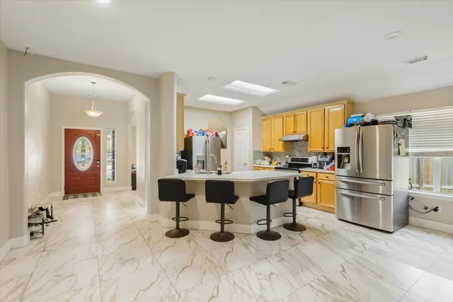 a living room with furniture a refrigerator and kitchen view