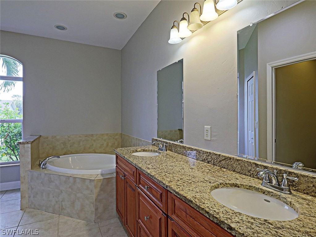 18242 Hemlock Road Fort Myers, FL 33967 - Photo 17 of 29 a bathroom with a granite countertop bathtub a sink and a mirror