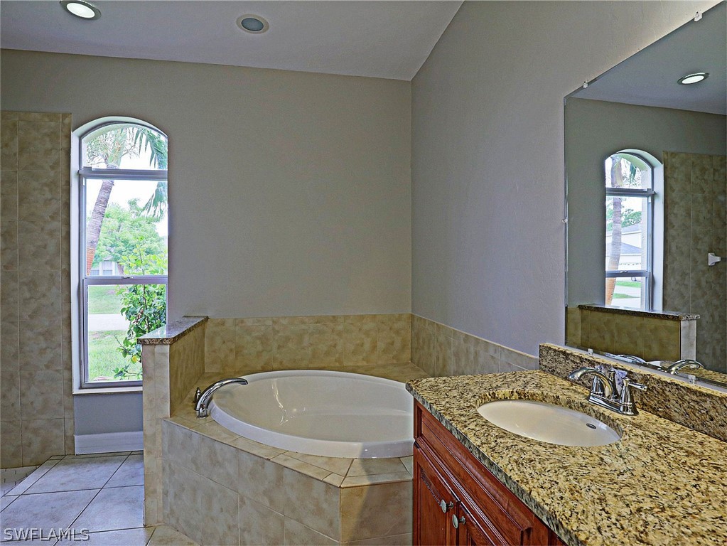 18242 Hemlock Road Fort Myers, FL 33967 - Photo 18 of 29 a bathroom with a granite countertop tub a double vanity sink and a window