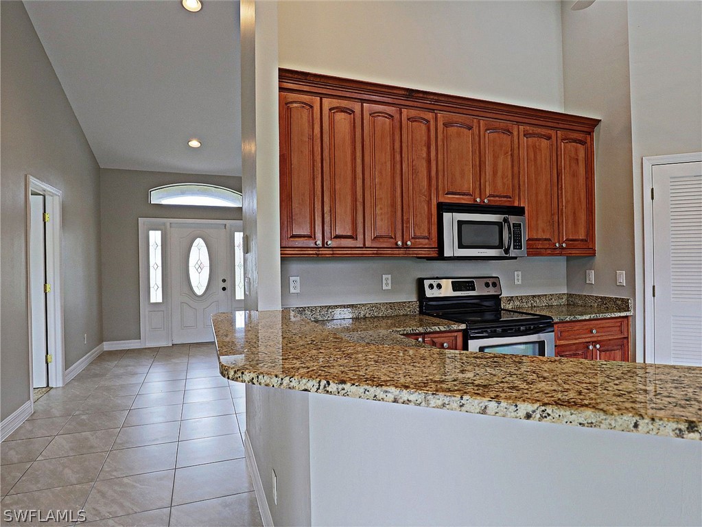 18242 Hemlock Road Fort Myers, FL 33967 - Photo 23 of 29 a kitchen with stainless steel appliances granite countertop a stove a sink and a microwave