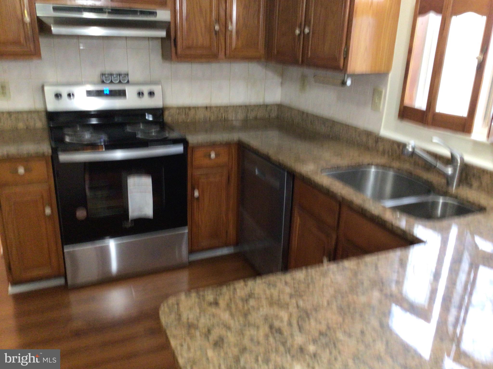 7679 Tuckerman Drive Hanover, MD 21076 - Photo 6 of 30 a kitchen with granite countertop a sink a stove and cabinets