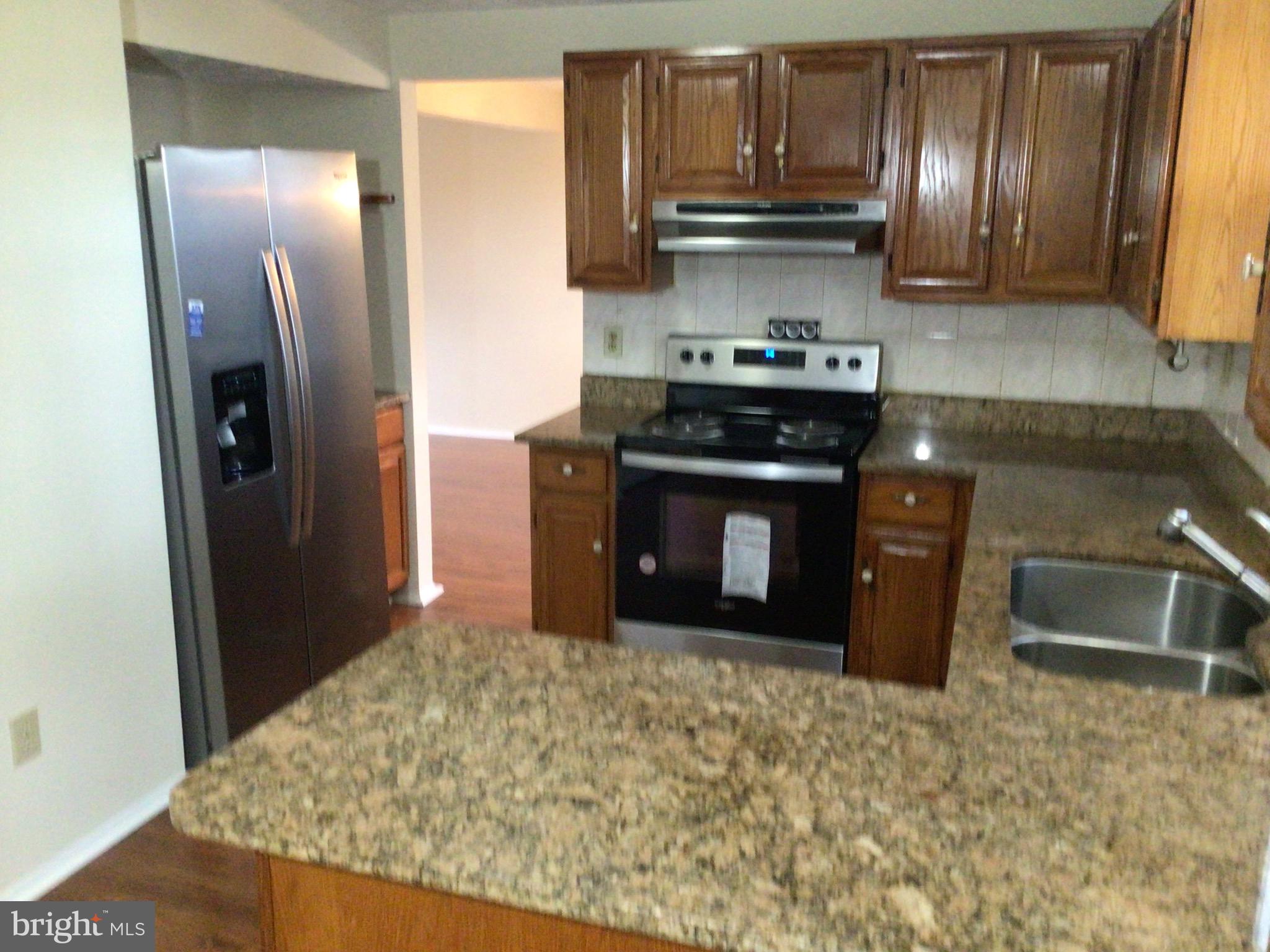 7679 Tuckerman Drive Hanover, MD 21076 - Photo 7 of 30 a kitchen with stainless steel appliances granite countertop a stove a refrigerator and a sink