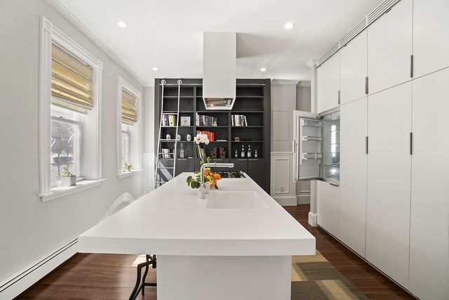 a view of kitchen island with stainless steel appliances refrigerator cabinets and wooden floor
