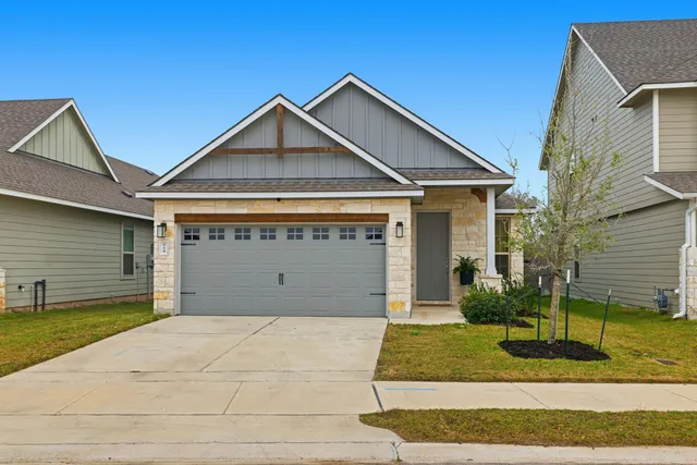 a view of a house with a yard plants and large tree