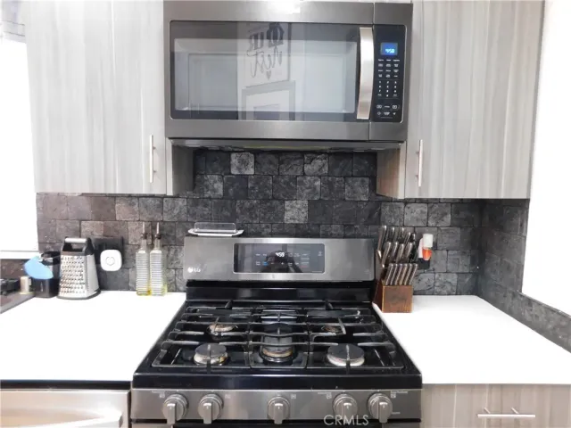 a kitchen with granite countertop a stove and a white cabinets