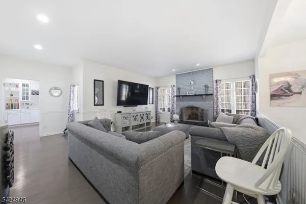 a living room with furniture kitchen view and a wooden floor