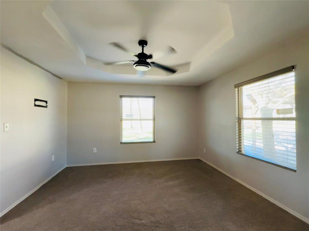 529 Northwest Private Road 147 Rice, TX 75155 - Photo 17 of 20 Unfurnished room with a tray ceiling, a ceiling fan, and dark colored carpet