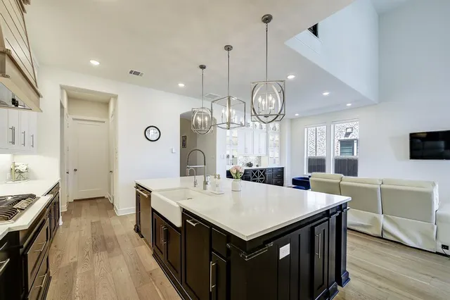 a large kitchen with granite countertop a sink and a stove top oven with wooden floor