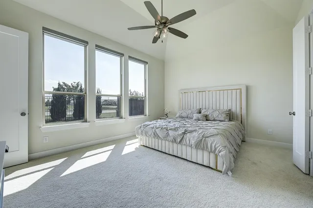 a bedroom with a large bed and a chandelier fan