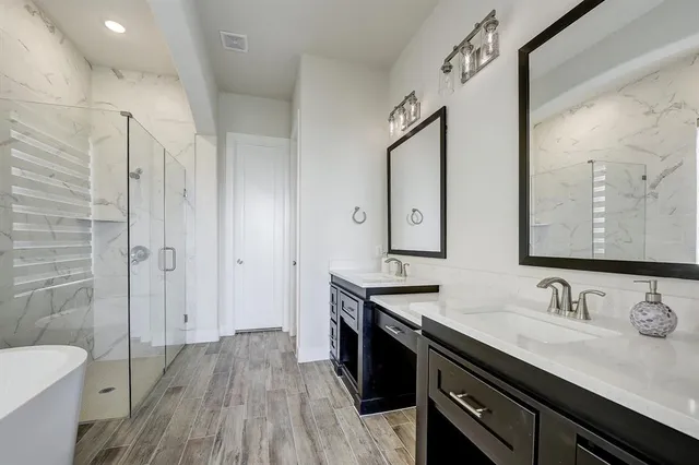 a spacious bathroom with a double vanity sink a mirror and a shower
