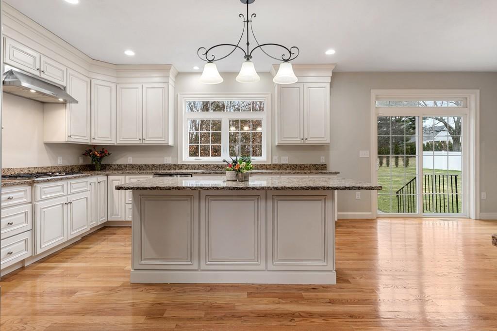 76 Deerfoot Road Southborough, MA 01772 - Photo 22 of 25 a kitchen with granite countertop a stove a sink and white cabinets with wooden floor