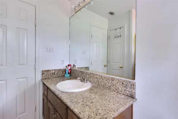 a bathroom with a granite countertop sink a mirror and shower