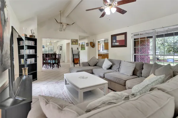a living room with furniture kitchen view and a large window