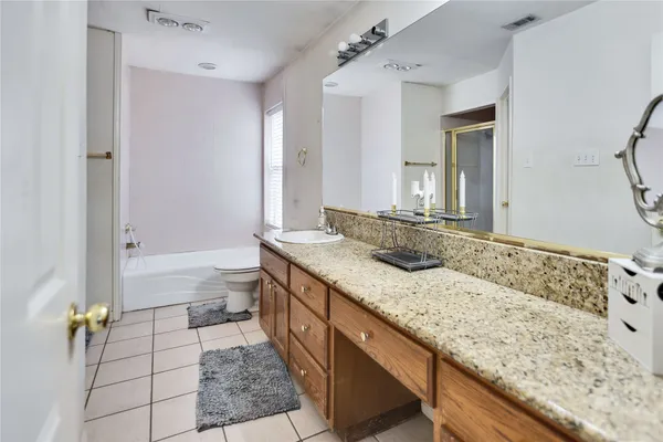 a bathroom with a granite countertop sink a toilet and bathtub