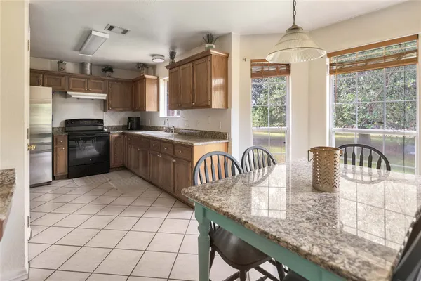 a kitchen with granite countertop a stove a sink dishwasher a dining table and chairs with wooden floor