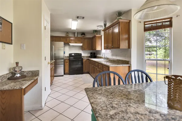 a kitchen with granite countertop a stove a sink and a refrigerator
