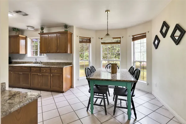 a kitchen with granite countertop a stove a table and chairs in it