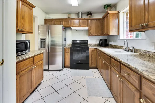 a kitchen with granite countertop a refrigerator stove and sink