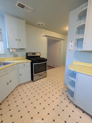 a kitchen with a sink a stove top oven and white cabinets